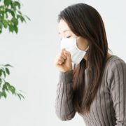 マスクをかけて咳をする女性