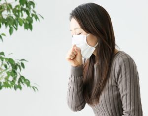 マスクをかけて咳をする女性